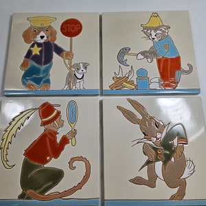Puede incluir: Cuatro azulejos de cerámica con ilustraciones coloridas de animales. El primer azulejo presenta un perro con un sombrero de policía y sosteniendo una señal de alto. El segundo azulejo muestra un gato con un sombrero amarillo y sosteniendo un pez. El tercer azulejo representa un mono con un sombrero rojo y sosteniendo un espejo. El cuarto azulejo muestra un conejo con una chaqueta verde.