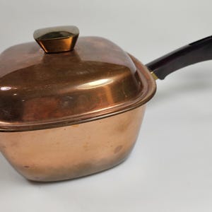 May include: A copper saucepan with a black plastic handle and a brass knob on the lid.