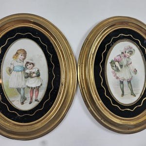 May include: Two antique oval framed prints. One print depicts two young girls in dresses, the other shows a girl with a basket of flowers. The frames are gold with a black inner border.