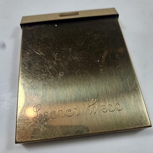 May include: A white ceramic mug with a black handle and the text "But First, Coffee" in a black, handwritten-style font. The mug is on a white surface.