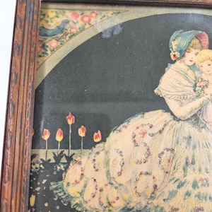May include: A framed vintage-style print featuring a person in a ruffled white gown holding a child, set against a dark background with orange tulips. The frame is made of dark brown wood with a textured, carved edge and a visible grain pattern.