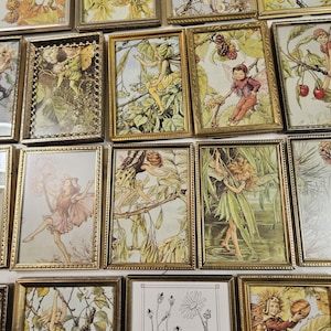 May include: A collection of framed fairy art prints. The prints feature illustrations of fairies in various poses, surrounded by flowers and foliage. The frames are gold-colored, and the artwork has a vintage aesthetic. The color palette includes greens, yellows, pinks, and browns.