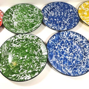 May include: A collection of eight round plates featuring a marbled enamel finish in red, green, blue, and yellow. Each plate displays a distinct white swirling pattern against a solid colored background with a thin black rim around the edge.
