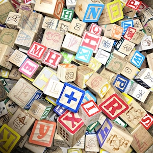 May include: A large collection of wooden alphabet blocks featuring various letters, numbers, and illustrations such as an umbrella, a bee, a mouse, a sailboat, an ice cream cone, a turtle, and a horse, all printed in red, blue, green, and black ink.