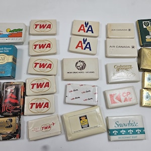 May include: Collection of vintage hotel and airline soaps, including brands like TWA, American Airlines, Air Canada, and Best Western. Various sizes and packaging, with some featuring travel-themed graphics and logos.