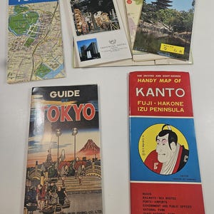 May include: A collection of vintage travel guides and maps for Tokyo and the Kanto region of Japan. The guides feature colorful covers with illustrations of landmarks, maps, and the text "Tokyo Walking Map" and "Guide of Tokyo".
