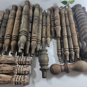 May include: A collection of wooden furniture legs, spindles, and finials in various shapes and sizes. The legs are unfinished and have a natural wood color.