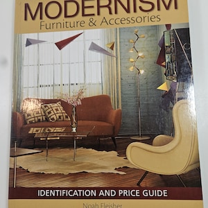 May include: A book titled "Warman's Modernism Furniture & Accessories" with the subtitle "Identification and Price Guide" by Noah Fleisher. The cover features a mid-century modern living room scene with a sofa, chair, and decorative elements.