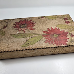 May include: A wooden box with a floral design. The box is painted with a light brown background and features red and green flowers.