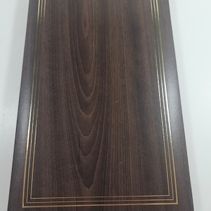 May include: A dark brown wooden photo album with a gold border.