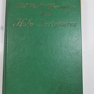 May include: A green hardcover book with gold lettering. The title "New World Translation of the Holy Scriptures" is embossed on the cover. The book has a textured surface and appears to be in good condition.