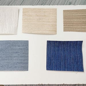 May include: Five samples of wallpaper in different colors and textures. The samples are arranged in two rows, with three samples in the top row and two samples in the bottom row. The samples are all rectangular and have a smooth surface. The colors of the samples are white, beige, brown, blue, and dark blue.