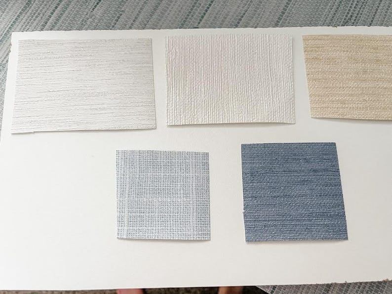 May include: Five samples of wallpaper in different colors and textures. The samples are arranged in two rows, with three samples in the top row and two samples in the bottom row. The samples are all rectangular and have a smooth, textured surface. The colors of the samples are white, beige, light blue, and dark blue.