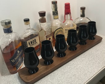 May include: A wooden serving tray with six clear glass whiskey glasses and seven bottles of whiskey. The bottles are labeled "Four Roses", "Maker's Mark", "Knob Creek", "Whistlepig", "Michter's", and two unidentifiable bottles.