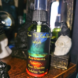 May include: A green glass bottle with a black spray nozzle and a black label that reads "From The Cauldron Witch" and "Aura Cleansing, Protection, Room Cleansing, Smokeless Spray".