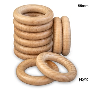 May include: A stack of 10 natural wood rings, each measuring 55mm in diameter. The rings are arranged in a pile, with the top ring slightly offset from the others. The rings are smooth and have a light brown color. The text "HYK designs" is visible in the lower right corner of the image.