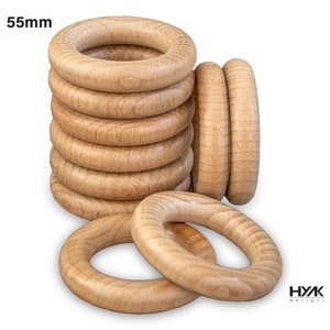 May include: A stack of 10 natural wood rings, each measuring 55mm in diameter. The rings are arranged in a pile, with the top ring slightly offset from the others. The rings are made of unfinished wood and have a smooth, polished surface.