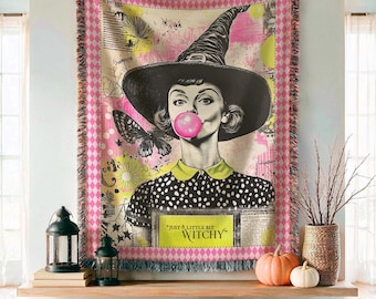 May include: A rectangular woven throw blanket featuring a black and white illustration of a person wearing a witch hat and polka dot shirt, blowing a pink bubble. The design includes a butterfly, yellow accents, and the text "JUST A LITTLE BIT WITCHY".