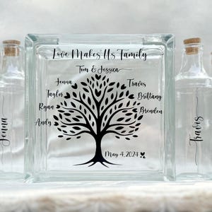 May include: A glass block with a family tree design and the text "Love Makes Us Family" with the names Tom & Jessica, Jenna, Taylor, Ryan, Andy, Travis, Brittany, and Brenden. The date May 4, 2024 is also included.