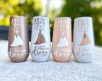 May include: Four stainless steel tumblers with a rose gold finish. Each tumbler has a white design with the text "She Said Yes" or "I Said Yes" and "Let's Find the Dress".