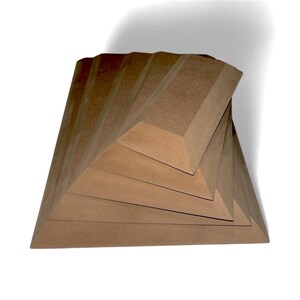 May include: A geometric sculpture with a layered, angular design. The artwork is constructed from a light brown material, featuring a series of stacked, triangular forms that create a spiral effect. The piece is set against a white background.