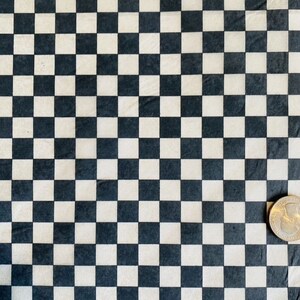May include: Black and white checkered pattern fabric. The fabric has a smooth, slightly textured surface. A US quarter is placed on the fabric for scale.