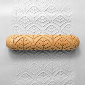 May include: A wooden rolling pin with a leaf pattern design. The rolling pin is used to create an embossed pattern on clay or dough.