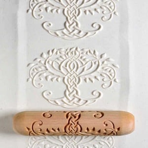 May include: A wooden rolling pin with a Celtic knot tree of life design. The rolling pin is used to create decorative patterns in dough.