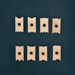 May include: Eight wooden blocks with a cutout in the centre. The blocks are arranged in two rows of four. The blocks are a light brown colour and have a slightly rough texture.