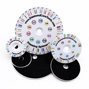 May include: Five white plastic trimming spinners with black centres and colourful markings. The largest spinner has a graduated scale in degrees and fractions. The spinners are labelled "Trimming Spinner" and "www.DiamondCoreTools.com".