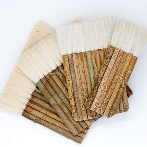 May include: A set of five natural bamboo handled paint brushes with white bristles. The handles are made of bamboo and have a natural wood grain pattern.