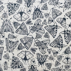 May include: A seamless pattern of black and white moths on a cream background. The moths are drawn in a detailed, intricate style, with various wing patterns and shapes.