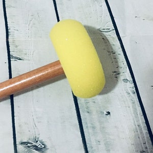 May include: A yellow foam paint roller attached to a wooden handle.