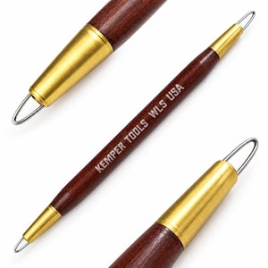 May include: A double-ended pottery tool with a dark brown wooden handle and brushed gold metal ferrules at each end. The tool features a thin, silver-coloured wire loop at both tips. The text KEMPER TOOLS WLS USA is printed on the wooden handle.