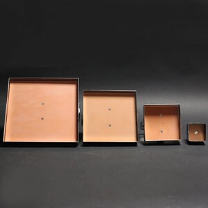May include: Four square metal frames with a light brown interior. The frames are arranged in descending size order from left to right.