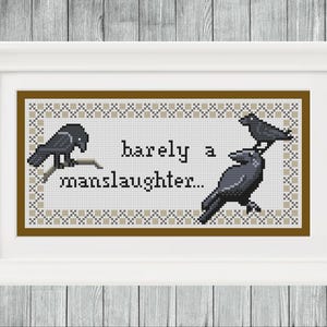 May include: Framed cross-stitch art featuring three black crows and the text "barely a manslaughter...". The artwork is in a brown and beige color scheme, set against a white background within a white frame. The background is a wooden surface.
