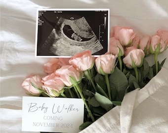 Puede incluir: Una tarjeta blanca con el texto "Baby Walker Coming November 2024" en ella. La tarjeta está sobre una bolsa de lona llena de rosas rosas. Una imagen de ultrasonido en blanco y negro es visible en el fondo.