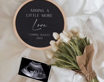 Op de afbeelding: Een zwart letterbord met witte tekst die "Adding a little more love coming August 2024" luidt. Naast het letterbord ligt een boeket witte tulpen en onder het letterbord bevindt zich een zwart-witte echografie.