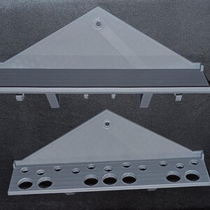 May include: A gray 3D printed wall-mounted organizer with a shelf and a row of holes for storing tools or other items.