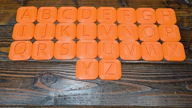 May include: Orange alphabet letter tiles with rounded edges. Each tile features a single uppercase letter in a white font.