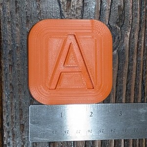 May include: Orange plastic letter A with a raised, textured surface. The letter is approximately 2 inches wide.