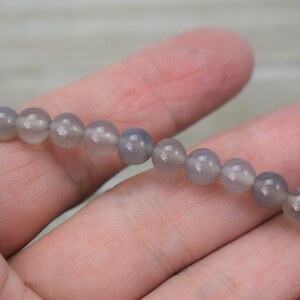 May include: A strand of grey agate beads, each bead is round and smooth.