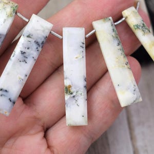 May include: A strand of white, green and black gemstone beads in a rectangular shape. The beads are strung on a silver chain.