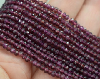 May include: A strand of deep purple faceted gemstone beads. The beads are small and round, and they have a shiny, polished finish.
