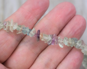May include: A strand of multi-colored fluorite chip beads. The beads are a mix of green, purple, and clear.