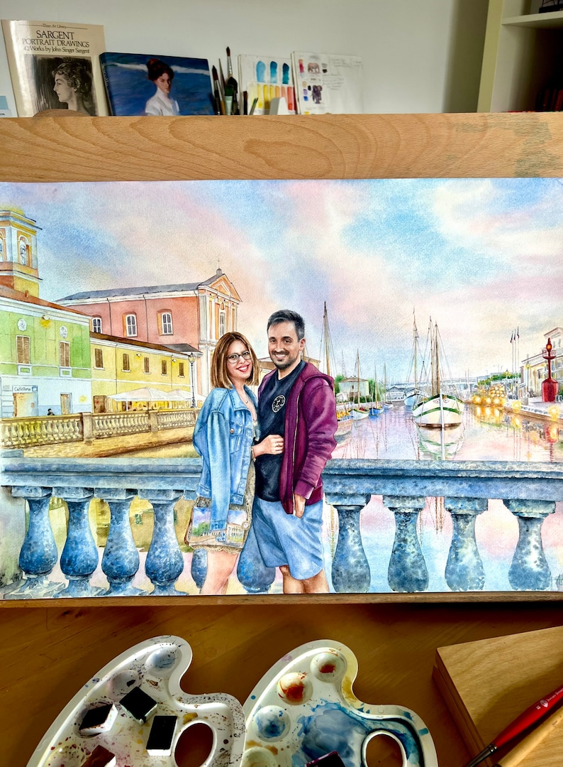 May include: Watercolour painting of a couple standing on a bridge in a European city. The couple are dressed in casual clothing and are smiling. The city is in the background, with buildings and boats visible. The painting is done in a realistic style and has a warm, inviting feel.
