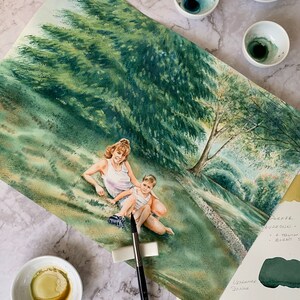 May include: A watercolor painting of a mother and child sitting in a grassy field. The woman is wearing a white tank top and the child is wearing a blue shirt. There are trees in the background and a small stream running through the field. The painting is on a white background and there are paintbrushes and paint palettes visible in the foreground.