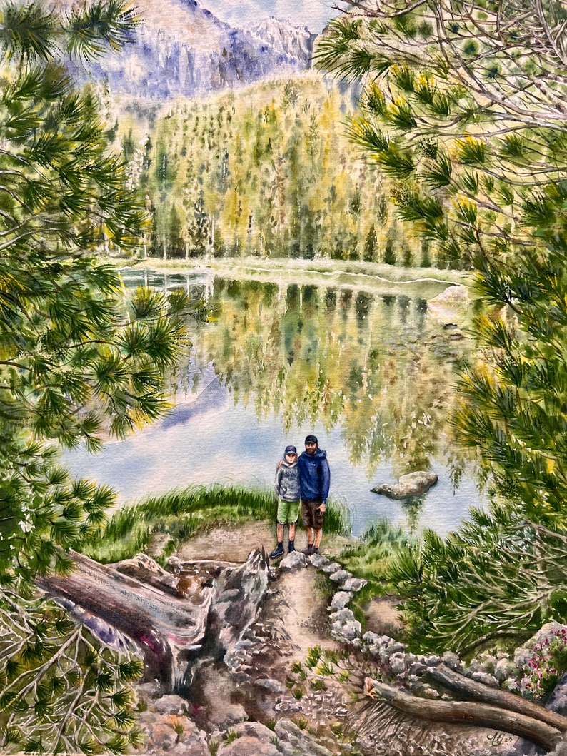 May include: A watercolor painting of two people standing on a path near a lake in a forest. The lake is surrounded by trees and mountains. The sky is blue and there are clouds in the sky.