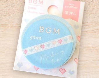 May include: A package of BGM masking tape. The tape is in a light blue circular shape with a white band featuring pink pixelated hearts. The package also includes the text "BGM", "5mm", and "Masking tape".