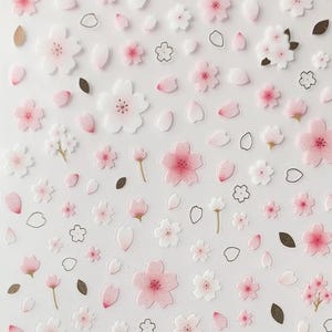 Könnte beinhalten: Bogen mit Suatelier-Aufklebern mit einem 'Deco Blossom'-Design. Die Aufkleber zeigen rosa und weiße Kirschblüten, Blütenblätter und Blätter. Der Text 'suatelier stickers no.1078 : deco blossom' ist oben auf dem Bogen aufgedruckt.